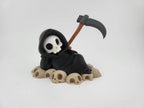 Grim Reaper Relaxing on Skulls – Tristo Mietitore sui Teschi