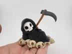 Grim Reaper Relaxing on Skulls – Tristo Mietitore sui Teschi